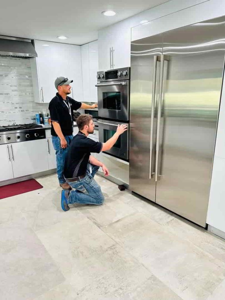 two man repairing an oven